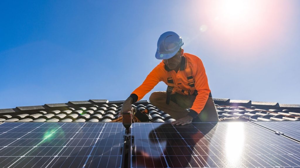 Asentaja asentamassa aurinkopaneeleita